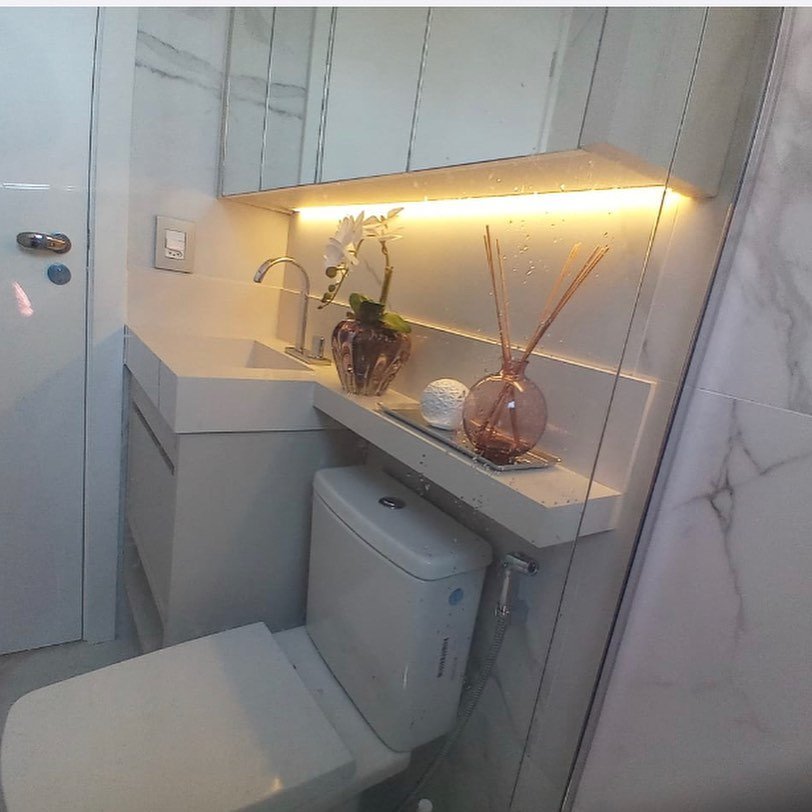Prateleira de banheiro com iluminação embutida e acabamento em mármore