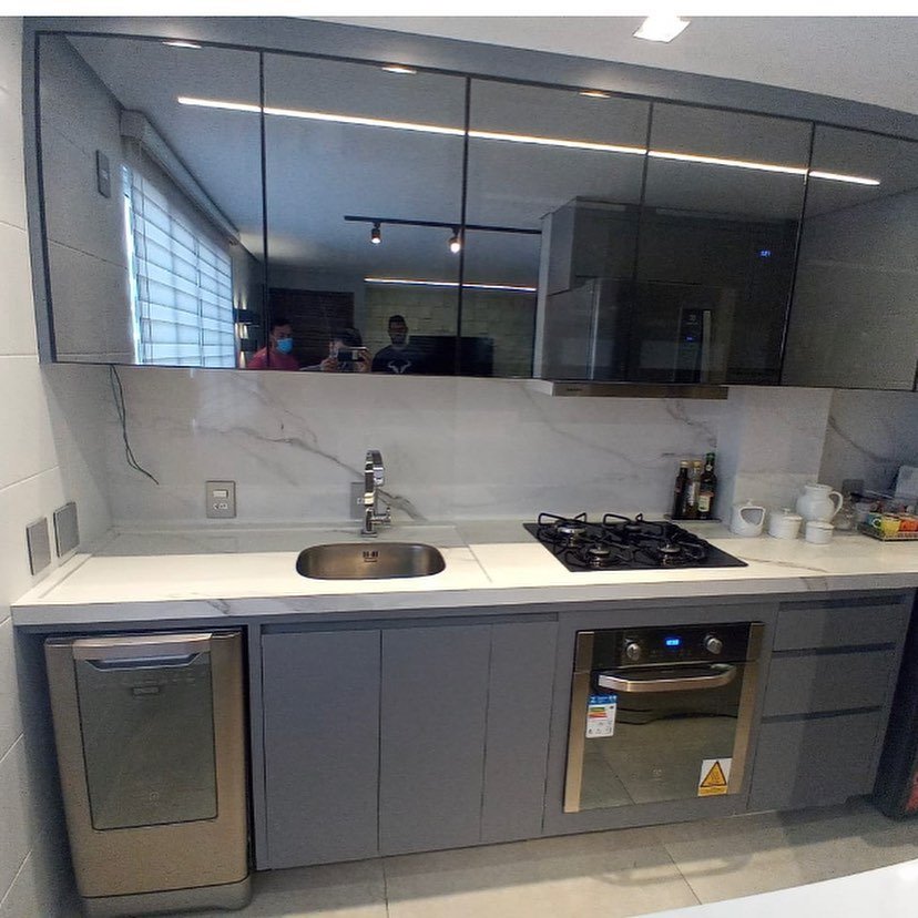 Cozinha planejada em cinza com armários superiores de vidro e revestimento de mármore